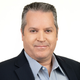 a man wearing a suit and tie smiling and looking at the camera