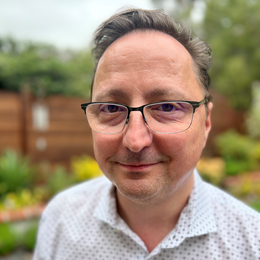 a man wearing glasses and smiling at the camera