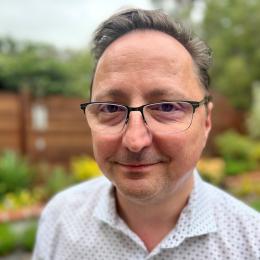a man wearing glasses and smiling at the camera